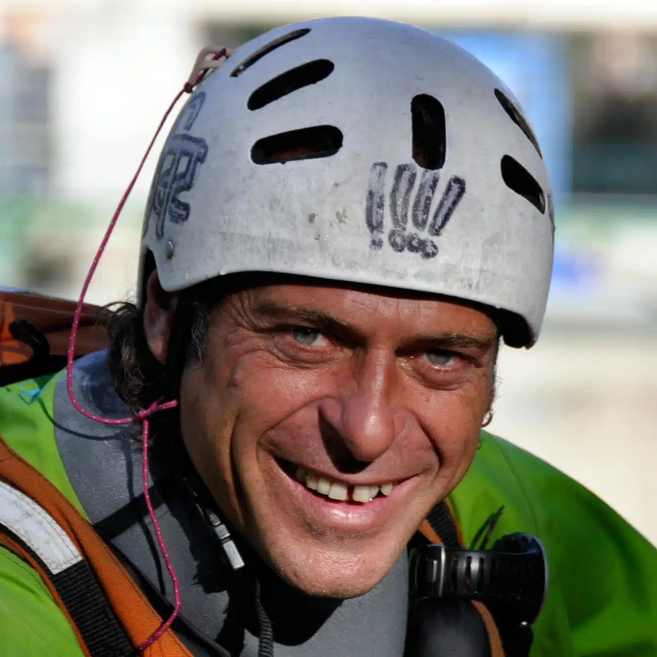 Soccorso Alluvionale e Fluviale Europa David Alemanni sorride, indossa un casco bianco con prese d'aria nere e una giacca verde, su uno sfondo leggermente sfocato. S.A.F.E.&reg; - River Rescue