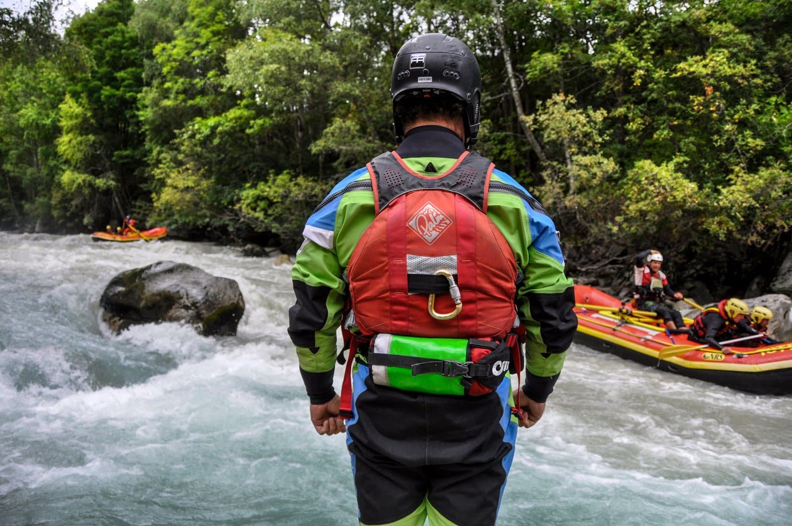 Flood and River Rescue Europe A rescue team member in protective gear is standing on the bank of a raging river, while in the background two rafts with people on board skillfully negotiate the rapids. S.A.F.E.® - River Rescue