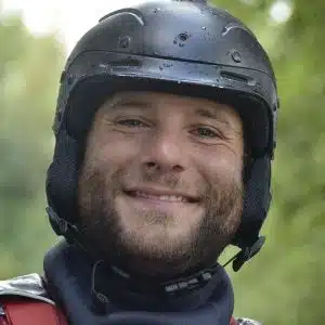 Soccorso Alluvionale e Fluviale Europa Miguel Naval è raggiante di eccitazione, indossa un casco e attrezzatura da esterno, sullo sfondo di uno splendido paesaggio naturale sfocato. S.A.F.E.® - River Rescue