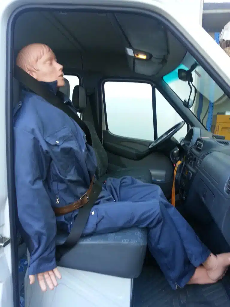 Soccorso Alluvionale e Fluviale Europa Un manichino in uniforme blu, parte del programma di addestramento Rescue 3, è seduto e allacciato al sedile del conducente di un veicolo. S.A.F.E.® - River Rescue