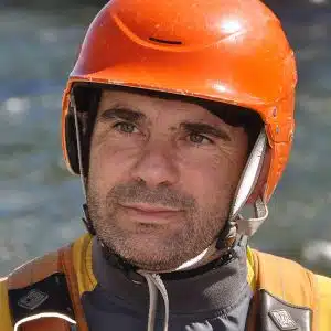 Soccorso Alluvionale e Fluviale Europa Andrea Remonti, con indosso un casco arancione e un giubbotto salvagente, è in piedi in riva al fiume, pronto per l'avventura. S.A.F.E.® - River Rescue
