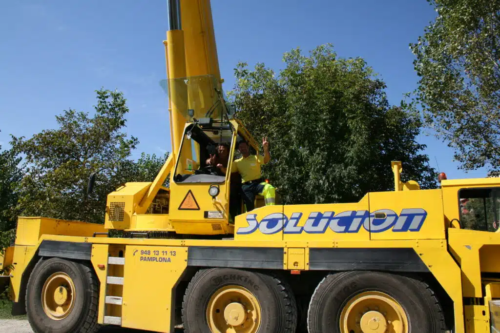 Soccorso Alluvionale e Fluviale Europa Una persona è seduta all'interno di un veicolo da cantiere giallo con la scritta "Solucions", uno strumento essenziale per le operazioni di Rescue 3, circondato da alberi. S.A.F.E.® - River Rescue