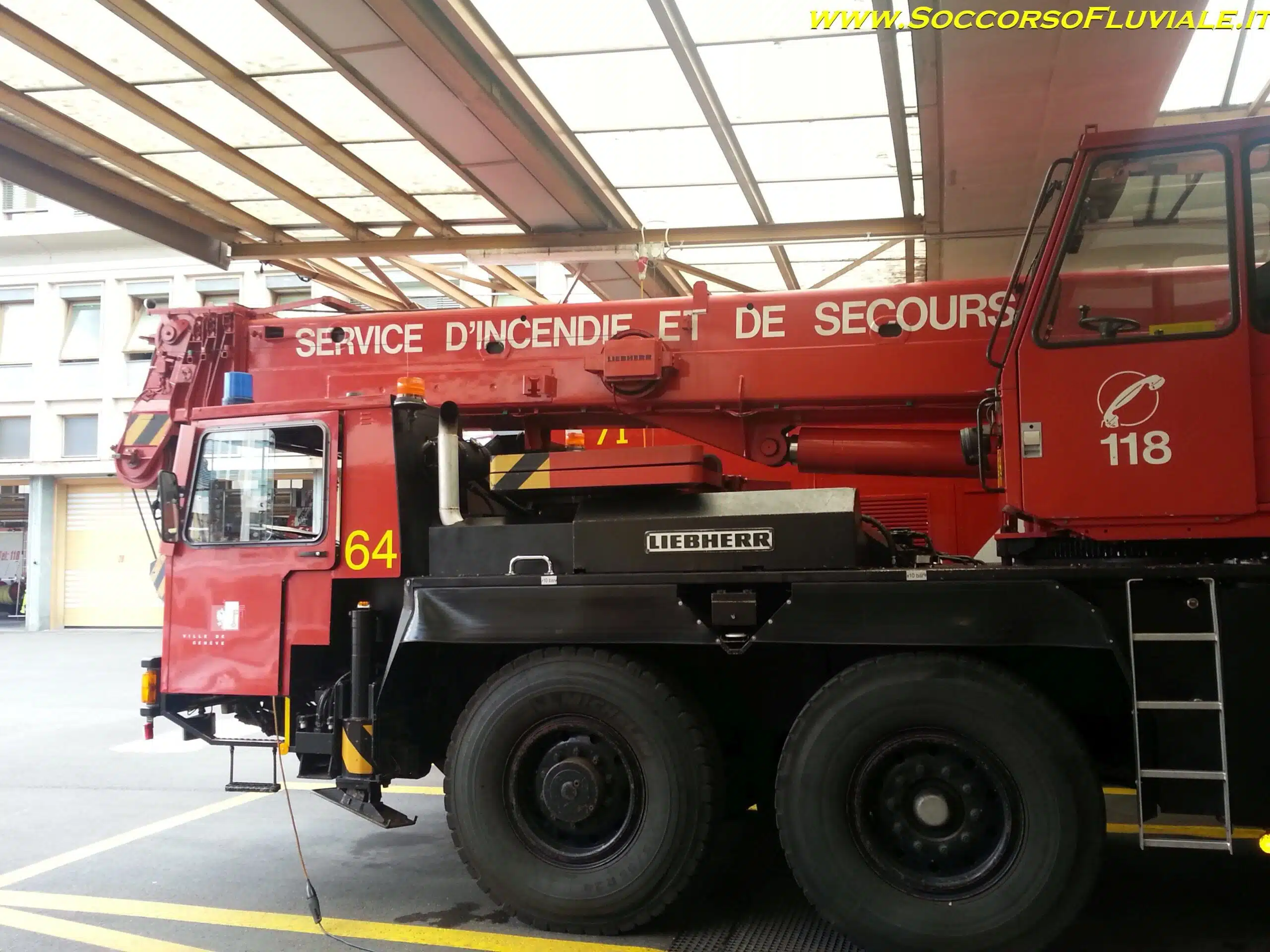 Soccorso Alluvionale e Fluviale Europa Un vivace camion dei pompieri rosso con la scritta "Service d'Incendie et de Secours" e "118" orgogliosamente esposto, è pronto per entrare in azione in un garage, a ricordare la prontezza dei Vigili del Fuoco della Svizzera. S.A.F.E.® - River Rescue