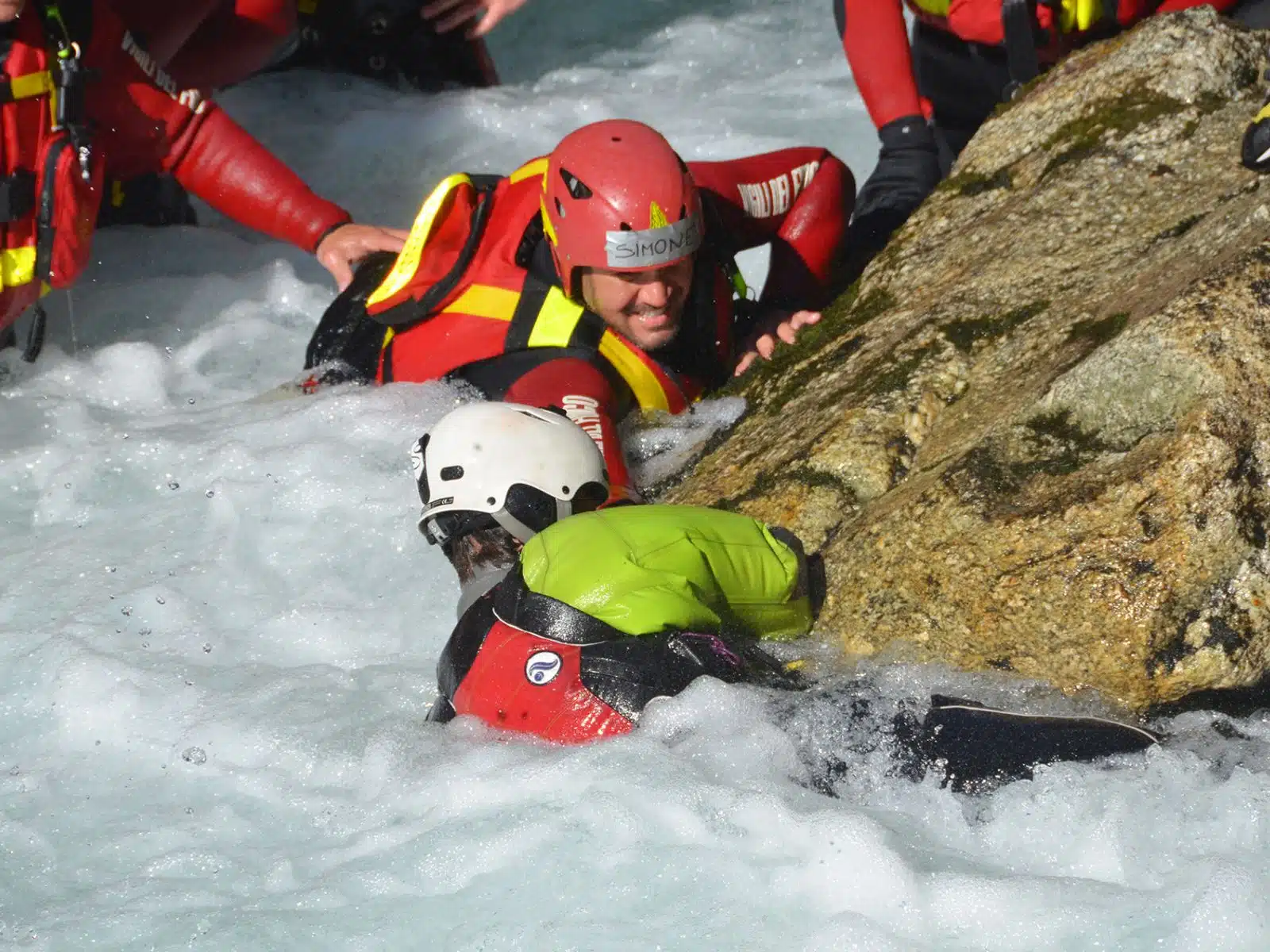 Soccorso Alluvionale e Fluviale Europa I soccorritori dotati dell'attrezzatura Rescue 3 prestano soccorso a una persona con una muta subacquea aggrappata a una roccia in mezzo alle acque impetuose. S.A.F.E.&reg; - River Rescue