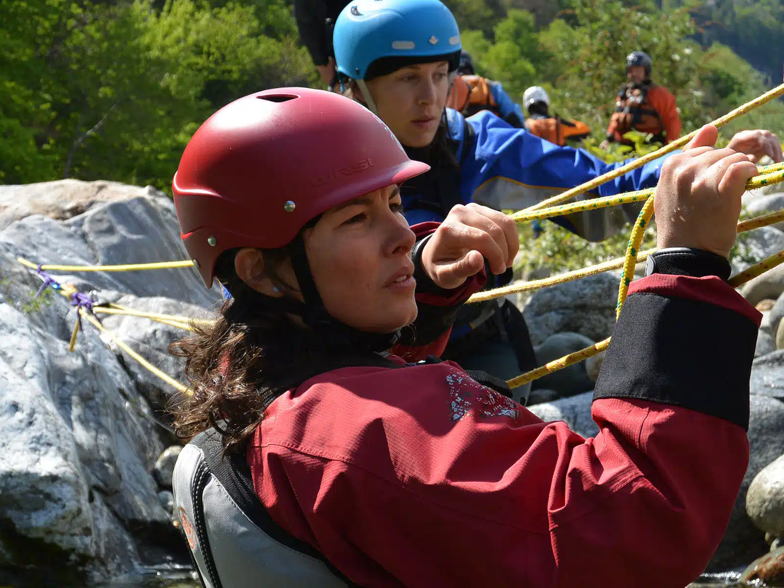 Soccorso Alluvionale e Fluviale Europa Due persone che indossano caschi e protezioni manovrano delle corde durante il rafting in un paesaggio roccioso e verdeggiante, dimostrando le competenze apprese durante il corso Rescue 3 Europe. S.A.F.E.® - River Rescue