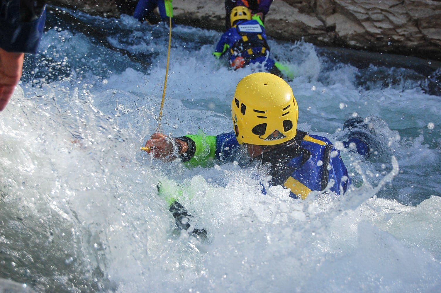 Soccorso Alluvionale e Fluviale Europa Indossando un casco giallo e una muta blu, l'individuo si destreggia abilmente tra le rapide di acqua bianca, afferrando sapientemente una corda. La sua tecnica riecheggia le linee guida di Rescue 3, dimostrando precisione e sicurezza. S.A.F.E.® - River Rescue