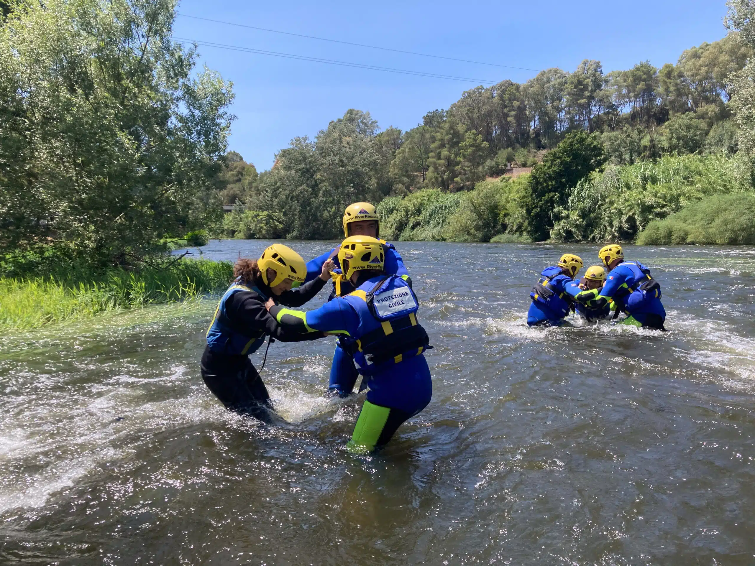 Soccorso Alluvionale e Fluviale Europa Persone con caschi e mute praticano le tecniche di soccorso 3 in un fiume circondato da alberi. S.A.F.E.® - River Rescue